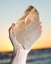 Woman holding huge natural Citrine Cathedral Quartz from Brazil in her hand at sunrise