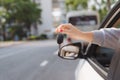 Woman holding the ignition keys of a car in her hand dangling them through the open side window