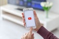 Woman holding iPhone with video service YouTube on screen