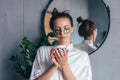 Woman holding a jar of eye patches while standing in the bathroom