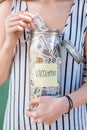 Woman holding jar full of money for summer vacation
