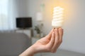 Woman holding lamp bulb in living room. Royalty Free Stock Photo