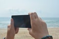 Woman holding landscape smartphone with blank screen while On the beach Royalty Free Stock Photo