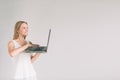 Woman holding laptop computer isolated on gray. Girl in white shirt, studio shot Royalty Free Stock Photo