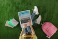 Woman holding laptop with open travel blogger site on artificial grass