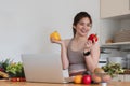 A woman is holding a laptop and two peppers in her hands Royalty Free Stock Photo