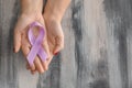 Woman holding lavender ribbon on wooden background. Cancer awareness concept