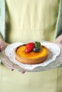 a woman holding a lemon tart with berries