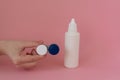 Contact lens case in a woman`s hand and bottle of solution on pink background Royalty Free Stock Photo