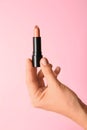 Woman holding light lipstick on color background