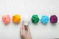 Woman holding lightbulb among colorful paper balls at white wooden table, top view. Idea concept Royalty Free Stock Photo