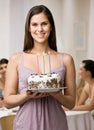 Woman holding lighted birthday cake