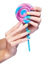 Woman is holding lollipop candy in hands with bright nails manic