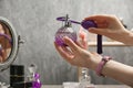 Woman holding luxurious perfume in crystal vintage bottle over dressing table, Royalty Free Stock Photo