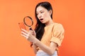 Woman holding a magnifying glass looking at her phone with a surprised expression Royalty Free Stock Photo