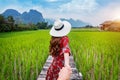 Woman holding man`s hand and leading him to Wooden path and green rice field in Vang Vieng, Laos Royalty Free Stock Photo