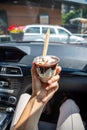 Woman holding the McDonalds McFlurry Ice Cream with chocolate in a car after drive thru. Drive thru concept