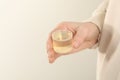 Woman holding measuring cup with syrup on light background, closeup. Cold medicine Royalty Free Stock Photo