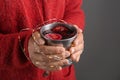 Woman holding metal cup of delicious mulled wine with Christmas garland on dark background, closeup Royalty Free Stock Photo