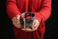 Woman holding metal cup of delicious mulled wine with Christmas garland on dark background, closeup Royalty Free Stock Photo