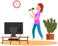 Woman holding microphone and singing music in karaoke. Girl stands with mike next to TV at home