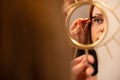 Woman Holding Mirror While Female Cosmetologist Using Mascara