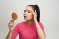 Woman holding a mirror, touch and worrying about her face Royalty Free Stock Photo