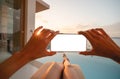 Woman holding mobile phone with blank screen while laying on sunbathing bed with beach view Royalty Free Stock Photo