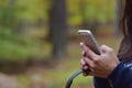 Woman holding mobile phone and headphones in hand against a blurry autumn forrest background Royalty Free Stock Photo