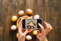 Woman holding mobile phone and making photo of eggs painted for Easter isolated on wooden background Royalty Free Stock Photo