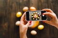 Woman holding mobile phone and making photo of eggs painted for Easter isolated on wooden background Royalty Free Stock Photo