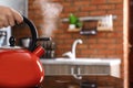 Woman holding modern kettle on stove in kitchen, closeup with space for