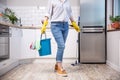 Woman holding mop and bucket with cleaning agents at home