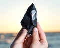 Woman holding Morion Smokey Quartz with Chlorite in her hand at sunrise