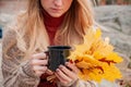 Woman holding mug of coffee in the hands outdoor. Beautiful woman drinking coffee in autumn park Royalty Free Stock Photo