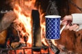 Young woman relaxing in front of cozy fireplace and warming up her feet in woolen socks in country house. Royalty Free Stock Photo