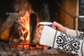 Young woman relaxing in front of cozy fireplace and warming up her feet in woolen socks in country house. Royalty Free Stock Photo