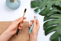 Woman holding natural bamboo and plastic toothbrushes over white table