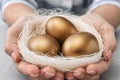 Woman holding nest with golden eggs over table Royalty Free Stock Photo