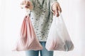 Woman holding in one hand groceries in reusable eco bag and in other vegetables in plastic polyethylene bag. Choose plastic free