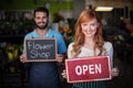 Woman holding open signboard and man holding slate with flower shop sign Royalty Free Stock Photo