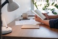 A woman holding and opening a blank notebook with coffee cup and papers on the table Royalty Free Stock Photo