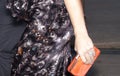 A woman holding a orange clutch purse