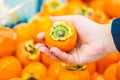 Woman holding orange date plum in the supermarket. Vegetables and fruits in the background. Shopping concept. Royalty Free Stock Photo