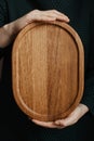 Woman holding an oval shaped wooden plate. Beautiful crockery made of real wood