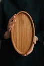 Woman holding an oval shaped wooden plate. Beautiful crockery made of real wood