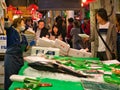 A woman holding a package talks to a stall holder in the busy Kanazawa Fish Market, Japan