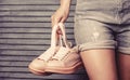 Woman holding shoes. Woman holding a pair of pink shoes. Girl with a beautiful waist in jeans shorts. Girl with a