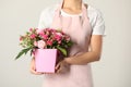 Woman holding paper gift box with flower bouquet on light background Royalty Free Stock Photo