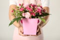 Woman holding paper gift box with flower bouquet on light background Royalty Free Stock Photo
